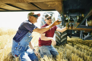 Two farmers inspecting Ziegler Ag farm equipment in a field, preventing damage.